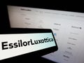 Cellphone with logo of French eyewear company EssilorLuxottica S.A. on screen in front of business website. Royalty Free Stock Photo