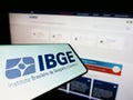 Cellphone with logo of Instituto Brasileiro de Geografia e Estatistica (IBGE) on screen with website.