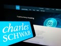 Cellphone with logo of US financial company The Charles Schwab Corporation on screen in front of website.