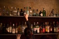 Waitress and bar shelves full of alcoholic beverages bottles