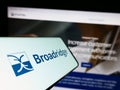 Mobile phone with logo of American company Broadridge Financial Solutions Inc. on screen in front of website.