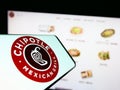 Mobile phone with logo of American company Chipotle Mexican Grill Inc. on screen in front of website.