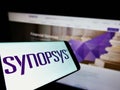 Mobile phone with logo of American technology company Synopsys Inc. on screen in front of business website.
