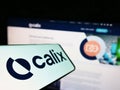 Mobile phone with logo of Australian technology company Calix Limited on screen in front of business website.