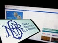 Mobile phone with logo of central bank Banca Nationala a Romaniei (BNR) on screen in front of business website.