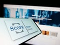 Mobile phone with logo of European fund rating company Scope Group on screen in front of business website.