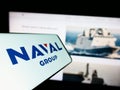 Mobile phone with logo of French defense company Naval Group S.A. on screen in front of business website.