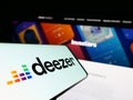Mobile phone with logo of French music streaming company Deezer S.A. on screen in front of website.