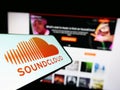 Mobile phone with logo of German music sharing company SoundCloud on screen in front of business website.