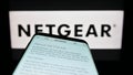 Mobile phone with web page of American computer networking company Netgear Inc. on screen in front of logo. Royalty Free Stock Photo