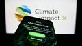 Mobile phone with webpage of carbon exchange Climate Impact X (CIX) on screen in front of business logo.