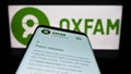 Mobile phone with webpage of confederation Oxfam International on screen in front of logo. Royalty Free Stock Photo