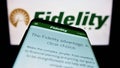 Mobile phone with webpage of US company Fidelity Investments (FMR LLC) on screen in front of business logo.