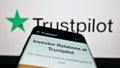 Mobile phone with website of review platform company Trustpilot Group plc on screen in front of business logo.