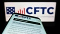 Mobile phone with website of US Commodity Futures Trading Commission (CFTC) on screen in front of logo.