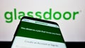 Mobile phone with website of US job review company Glassdoor Inc. on screen in front of business logo.