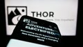 Mobile phone with website of US RV manufacturing company Thor Industries Inc. on screen in front of logo.
