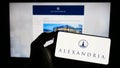 Person holding cellphone with logo of American company Alexandria Real Estate Equities Inc. on screen in front of webpage.