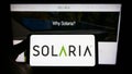 Person holding cellphone with logo of American solar panel company Solaria Corporation on screen in front of webpage.