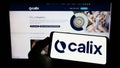 Person holding cellphone with logo of Australian technology company Calix Limited on screen in front of business webpage. Royalty Free Stock Photo