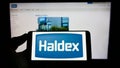 Person holding cellphone with logo of automotive company Haldex Europe SAS on screen in front of business webpage. Royalty Free Stock Photo