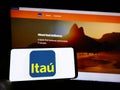 Person holding cellphone with logo of Brazilian company Itau Unibanco Holding SA on screen in front of business webpage. Royalty Free Stock Photo
