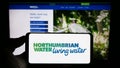 Person holding cellphone with logo of British company Northumbrian Water Limited on screen in front of business webpage. Royalty Free Stock Photo