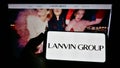 Person holding cellphone with logo of Chinese fashion company Lanvin Group on screen in front of business webpage.