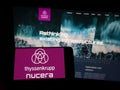 Person holding cellphone with logo of company thyssenkrupp nucera AG Co. KGaA on screen in front of business webpage.