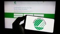 Person holding cellphone with logo of environmental certification Nordic Ecolabel on screen in front of webpage. Royalty Free Stock Photo