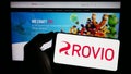 Person holding cellphone with logo of Finnish games company Rovio Entertainment Oyj on screen in front of webpage. Royalty Free Stock Photo