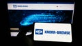Person holding cellphone with logo of German manufacturing company Knorr-Bremse AG on screen in front of business webpage. Royalty Free Stock Photo