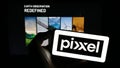 Person holding cellphone with logo of Indian company Pixxel Space Technologies Inc. on screen in front of webpage.