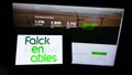 Person holding cellphone with logo of Italian energy company Falck Renewables S.p.A. on screen in front of webpage.