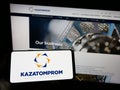 Person holding cellphone with logo of Kazakh uranium mining company Kazatomprom on screen in front of business web page. Royalty Free Stock Photo
