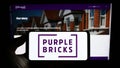 Person holding cellphone with logo of real estate company Purplebricks Group plc on screen in front of business webpage. Royalty Free Stock Photo