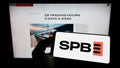 Person holding cellphone with logo of Russian financial marketplace SPB Exchange on screen in front of business webpage.