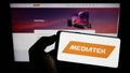 Person holding cellphone with logo of Taiwanese semiconductor company MediaTek Inc. on screen in front of webpage.