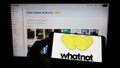 Person holding cellphone with logo of US e-commerce company Whatnot Inc. on screen in front of business webpage.
