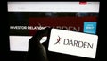 Person holding cellphone with logo of US gastronomy company Darden Restaurants Inc. on screen in front of webpage.