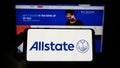 Person holding cellphone with logo of US insurance company The Allstate Corporation on screen in front of web page. Royalty Free Stock Photo
