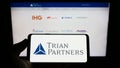 Person holding cellphone with logo of US investment company Trian Fund Management L.P. on screen in front of webpage. Royalty Free Stock Photo