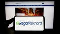 Person holding cellphone with logo of US motor company Regal Rexnord Corporation on screen in front of business webpage.