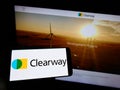 Person holding cellphone with logo of US renewables company Clearway Energy Inc. on screen in front of business webpage.
