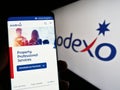 Person holding cellphone with web page of French facility management company Sodexo S.A. on screen with logo.