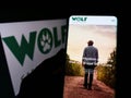 Person holding cellphone with webpage of company Wolf Carbon Solutions on screen in front of business logo.