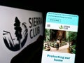 Person holding cellphone with webpage of US environmental organization Sierra Club on screen in front of logo.