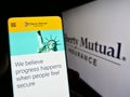 Person holding cellphone with webpage of US insurance company Liberty Mutual Group on screen in front of logo.