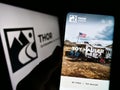 Person holding cellphone with webpage of US RV manufacturing company Thor Industries Inc. on screen with logo.