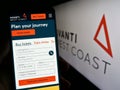 Person holding cellphone with website of British train company Avanti West Coast on screen in front of logo.